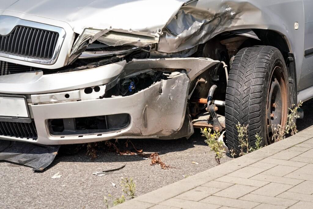 Silbernes Auto mit stark beschädigter Front und verbogenem Rad, am Bordstein geparkt, markiert als "Automatisch gespeicherter Entwurf".